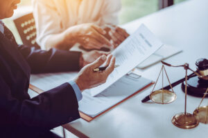 A business lawyer in Winston-Salem reviewing paperwork with a client at a white desk.