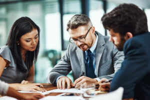A corporate attorney discussing and reviewing a paper with two business owners in Winston-Salem.
